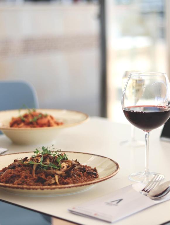 a table with a plate of food and a glass of wine at Cavalieri Art Hotel in St. Julianʼs