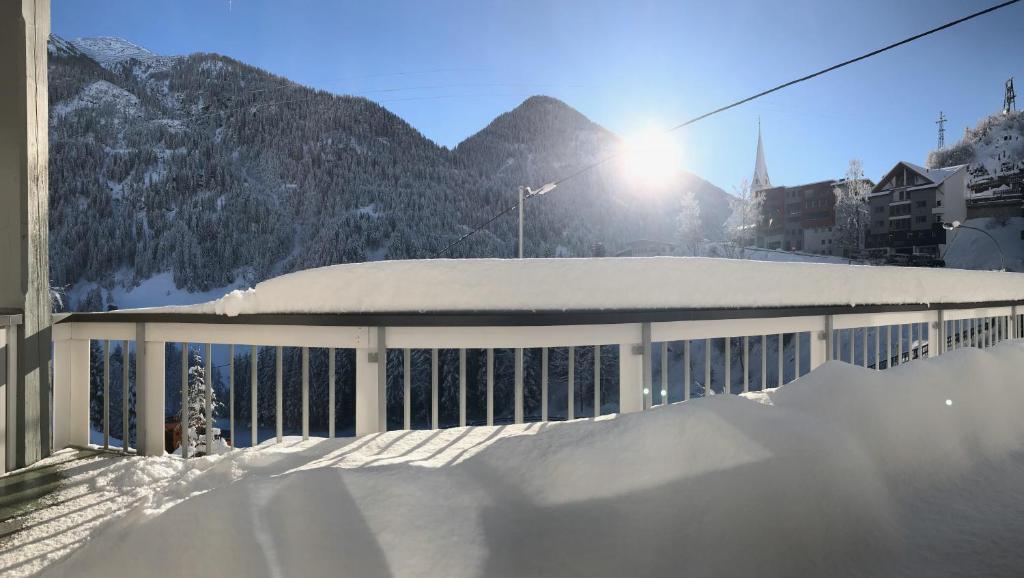 a building covered in snow with mountains in the background at Ferienhaus Jäger in Kappl