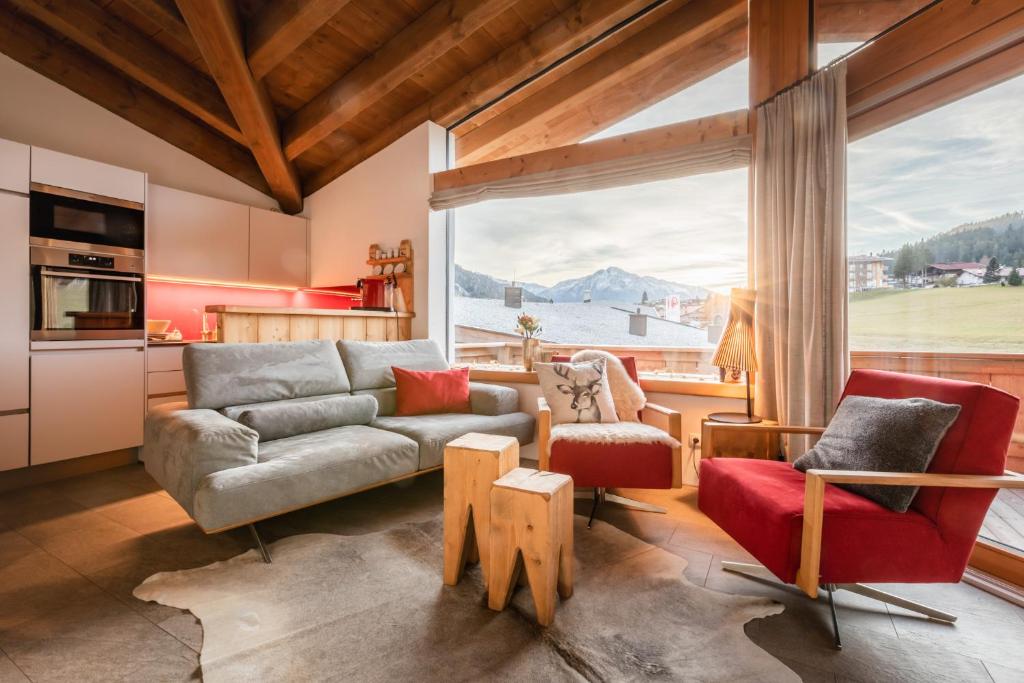 a living room with a couch and chairs and a large window at Löwen Chalets in Seefeld in Tirol