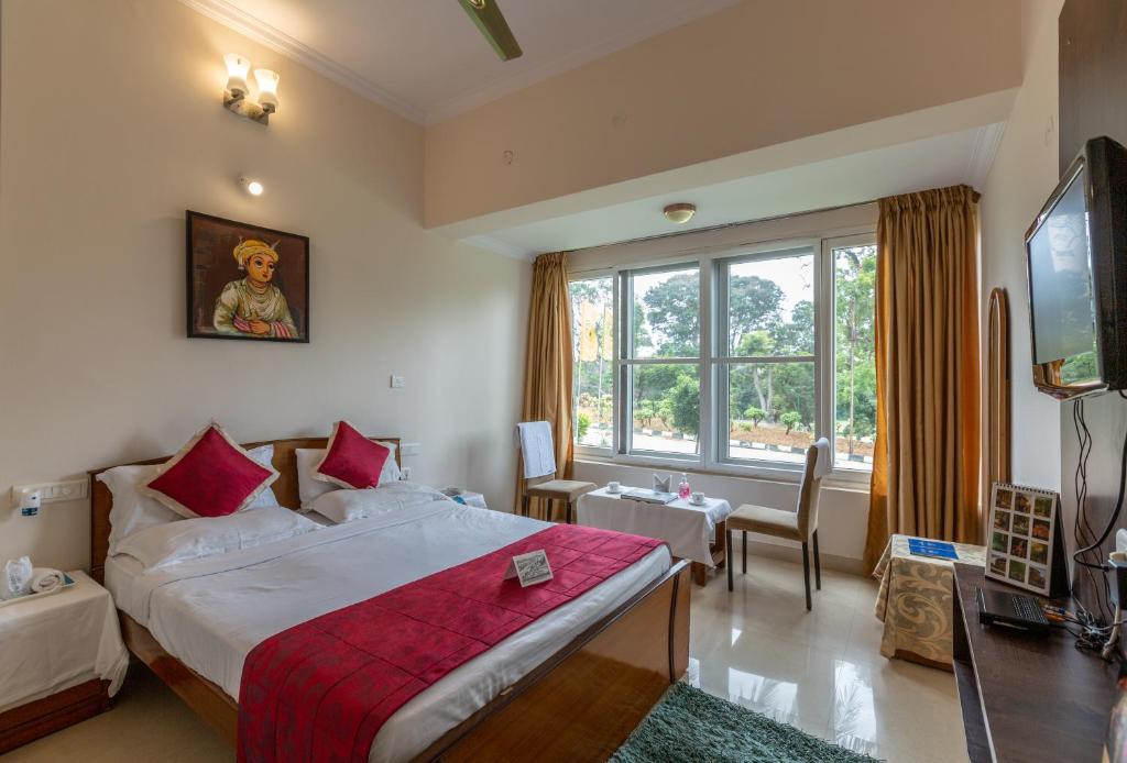 a hotel room with a bed and a television at KSTDC Hotel Mayura Kauvery KRS in Hosa Kannambādi