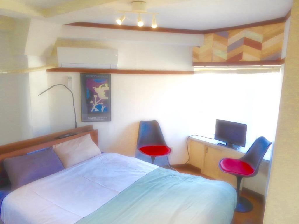 um quarto com uma cama, uma secretária e 2 cadeiras em Dazaifu - Apartment / Vacation STAY 36947 em Dazaifu
