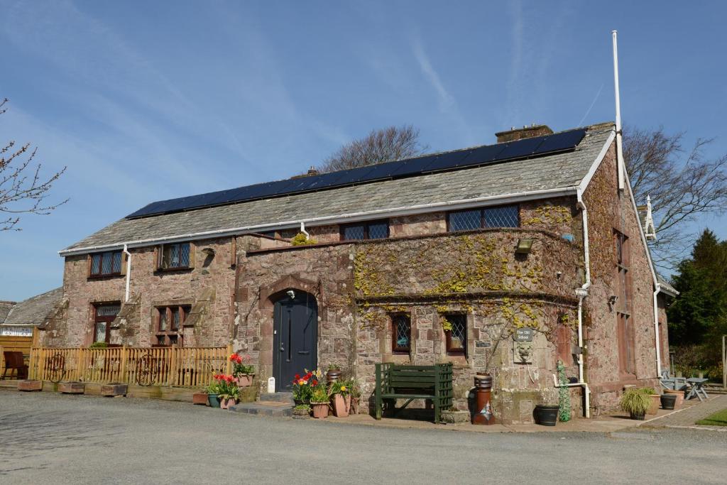 an old brick building with a bench in front of it at The Old School and Betty's B&B in Holmrook