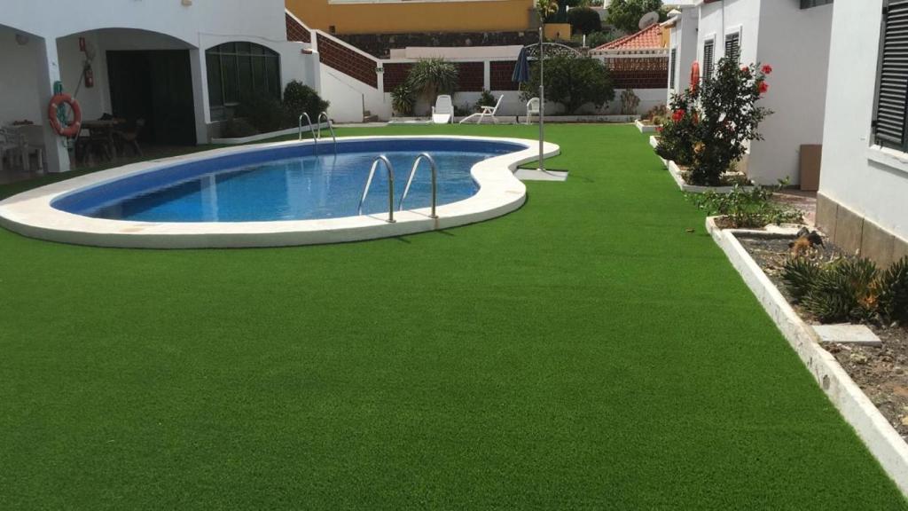 a yard with green grass and a swimming pool at Apartamentos Beatriz in Playa del Ingles