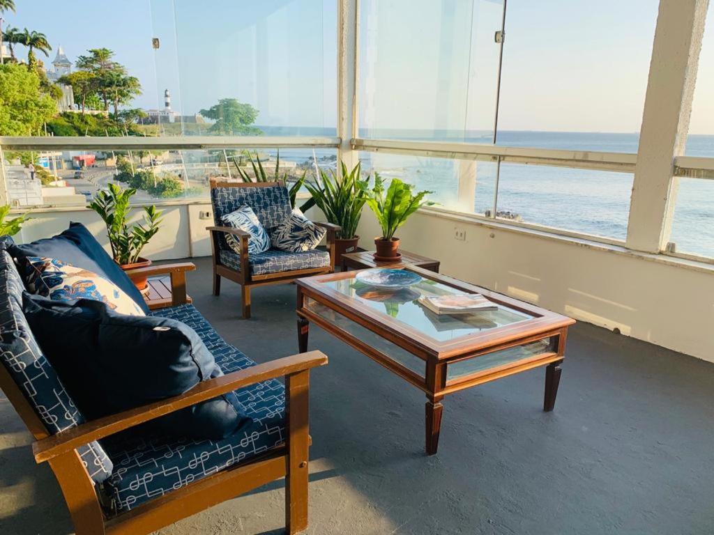 een woonkamer met stoelen en een tafel en uitzicht op de oceaan bij Manhatã Hostel in Salvador