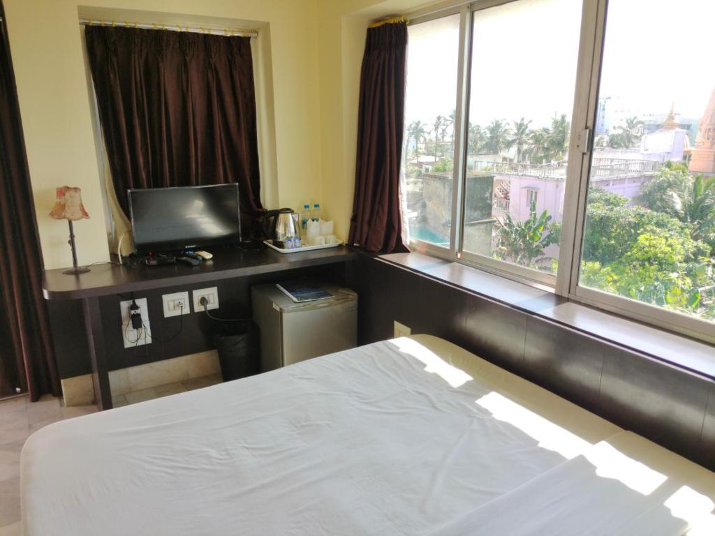 a bedroom with a bed and a large window at Hotel Gandhara in Puri