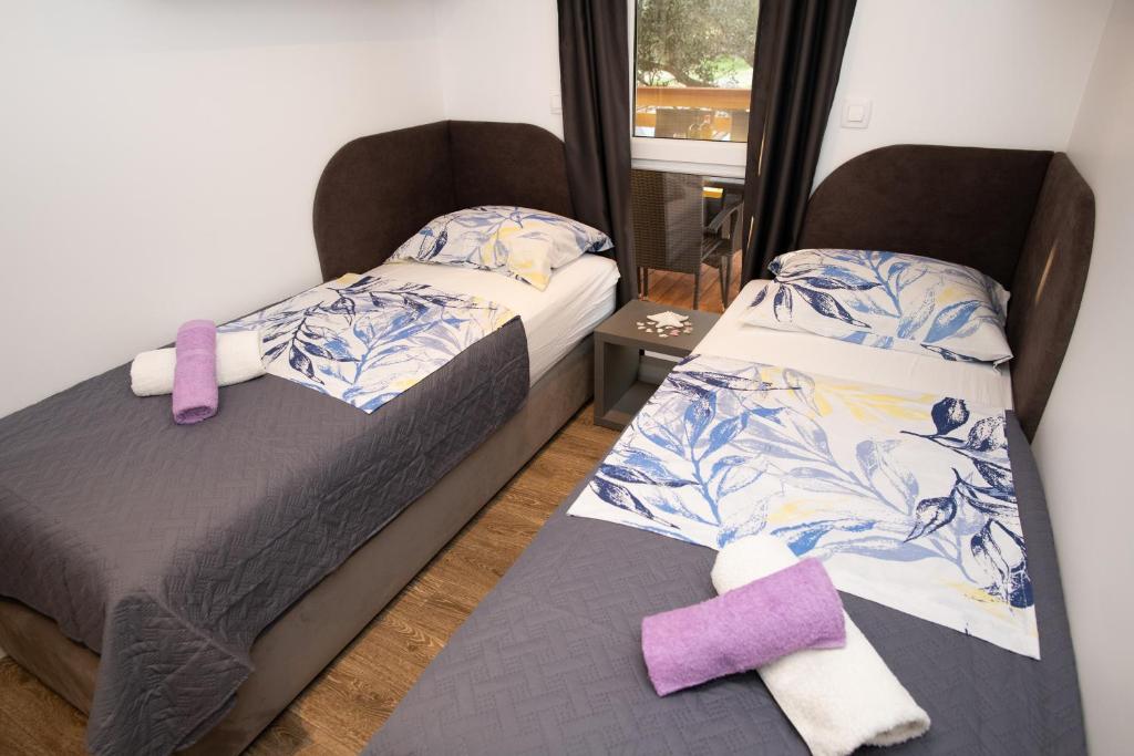 Authentic Camping Dalmatia في بيروفاتش: سريرين في غرفة صغيرة مع وسائد أرجوانية