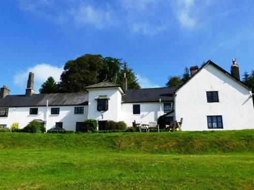 une grande maison blanche sur un champ verdoyant dans l'établissement Simonsbath House Hotel, à Simonsbath