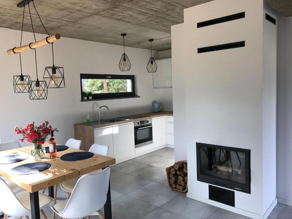 a kitchen with a dining table and a fireplace at Sosnowe Zacisze in Sasino