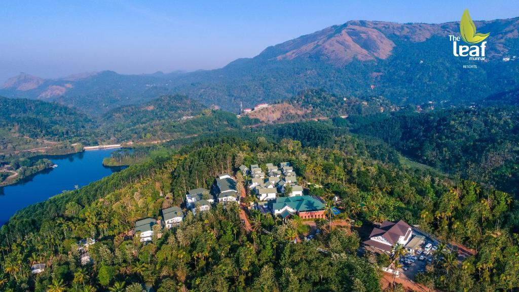 an aerial view of a resort on a hill next to a lake at The Leaf Munnar in Munnar