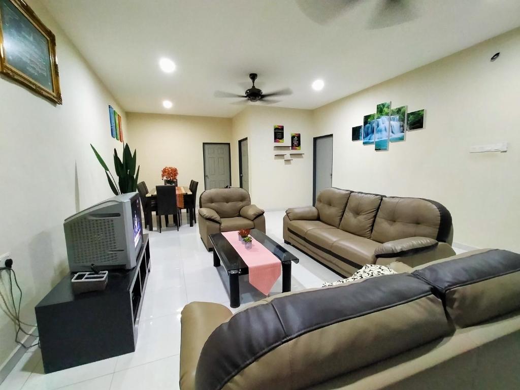 a living room with a couch and a tv in it at Fathi Homestay, Pagoh Jaya in Pagoh