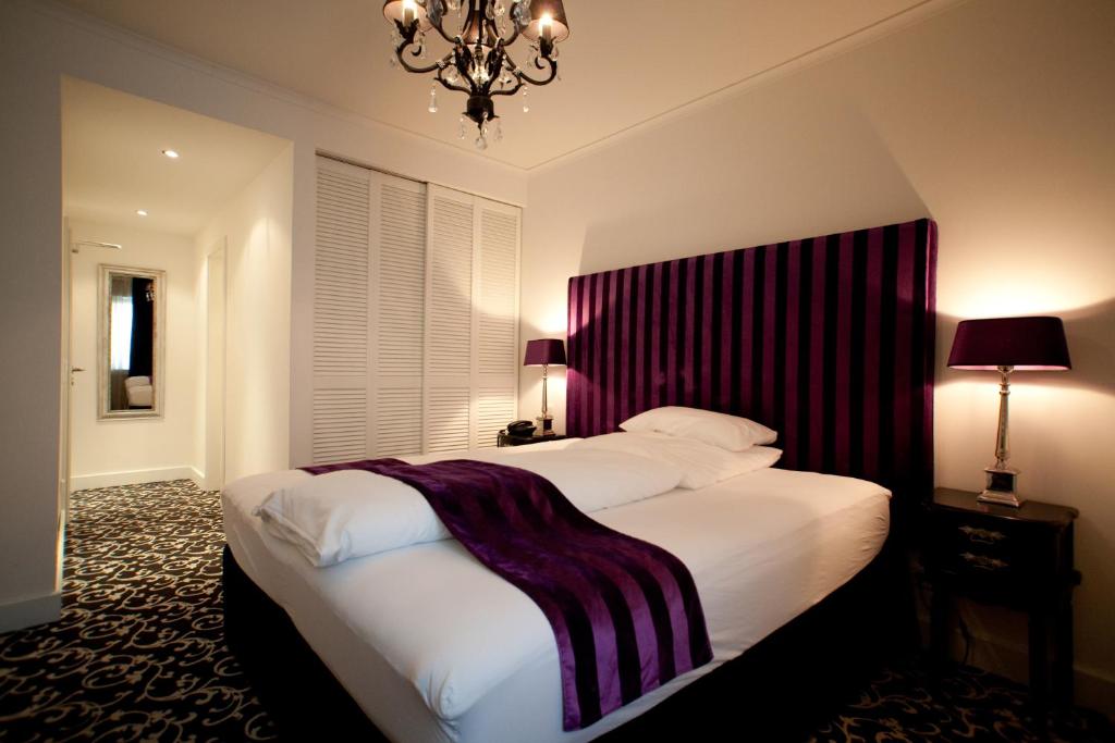 a bedroom with a large bed and a chandelier at Hotel Aleksandra in Düsseldorf