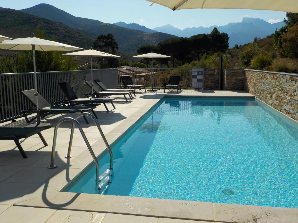 a swimming pool with chairs and umbrellas on a patio at Appartements Candella in Galeria