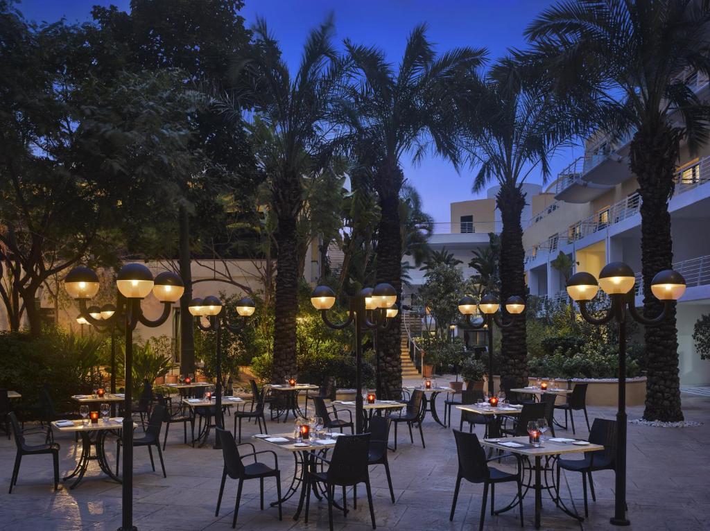 a patio with tables and chairs and palm trees at InterContinental Malta by IHG in St Julian's