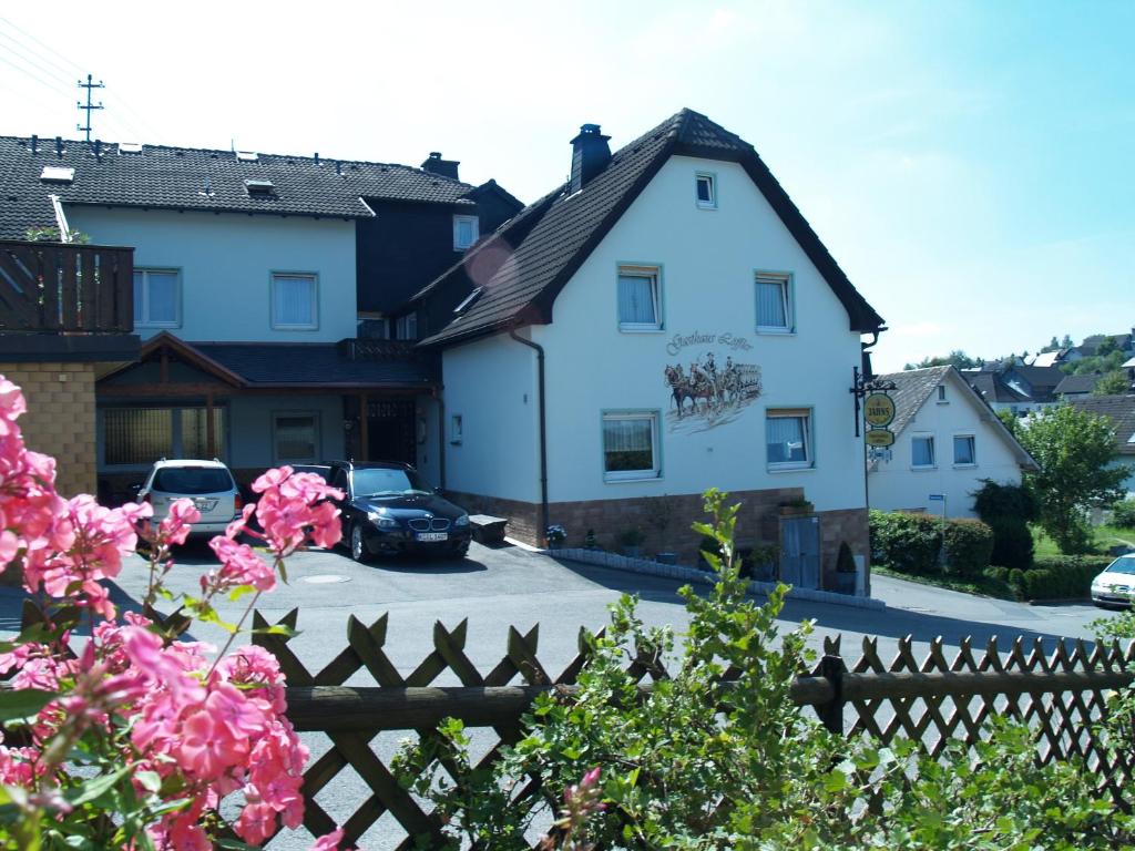 a white house with a car parked in a parking lot at Pension Löffler in Steinbach am Wald