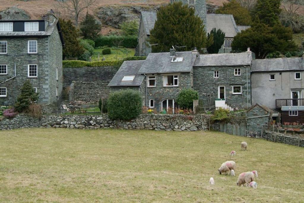 um grupo de ovinos pastando em um campo em frente a uma casa em Church Bank em Chapel Stile