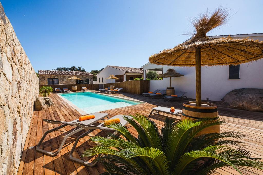 a pool with an umbrella and chairs and a swimming pool at Résidence Petra d'Oro - Villa Chiappa in Porto-Vecchio