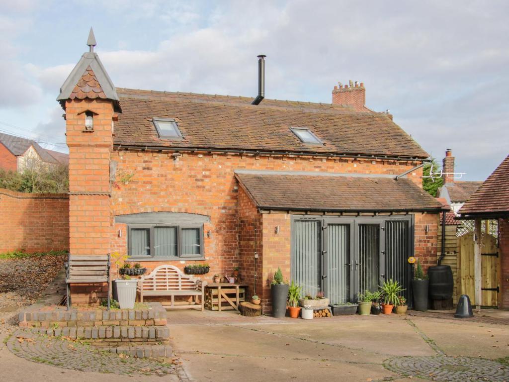 ein Backsteinhaus mit einem Fenster und einer Terrasse in der Unterkunft Bank House Barn in Shrewsbury