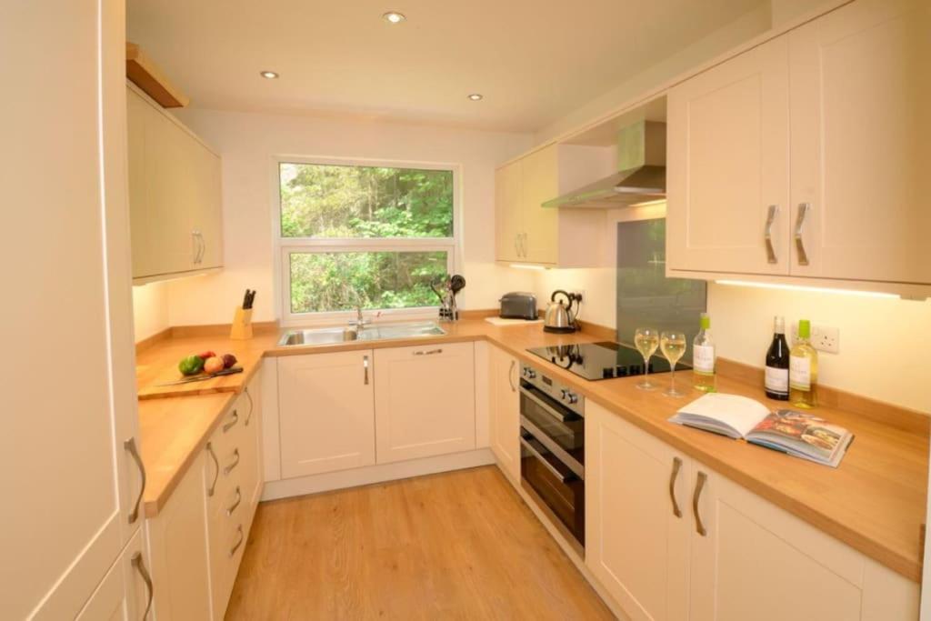 a kitchen with white cabinets and a window at Lingmell Fell View, Chapel Stile in Chapel Stile