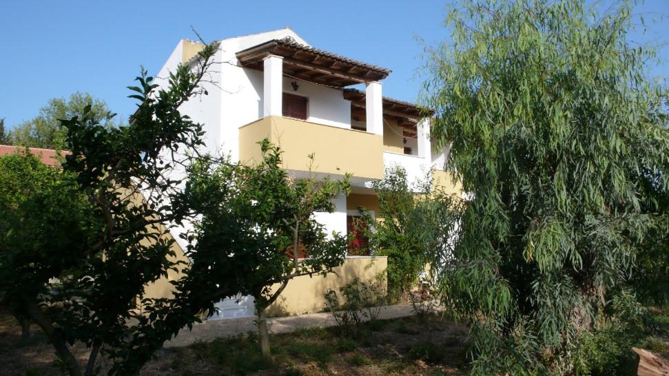 una casa bianca con degli alberi di fronte di Socrates Studios & Apartments ad Acharavi