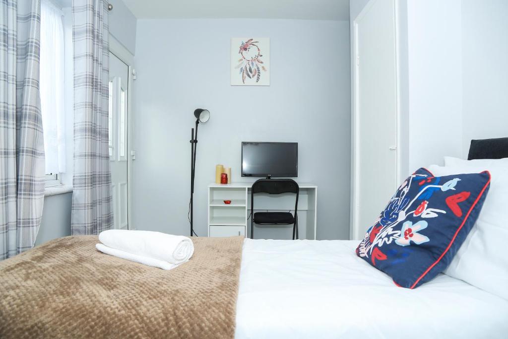 a white bedroom with a bed and a television at Wilmington Lodge Dartford London in Kent