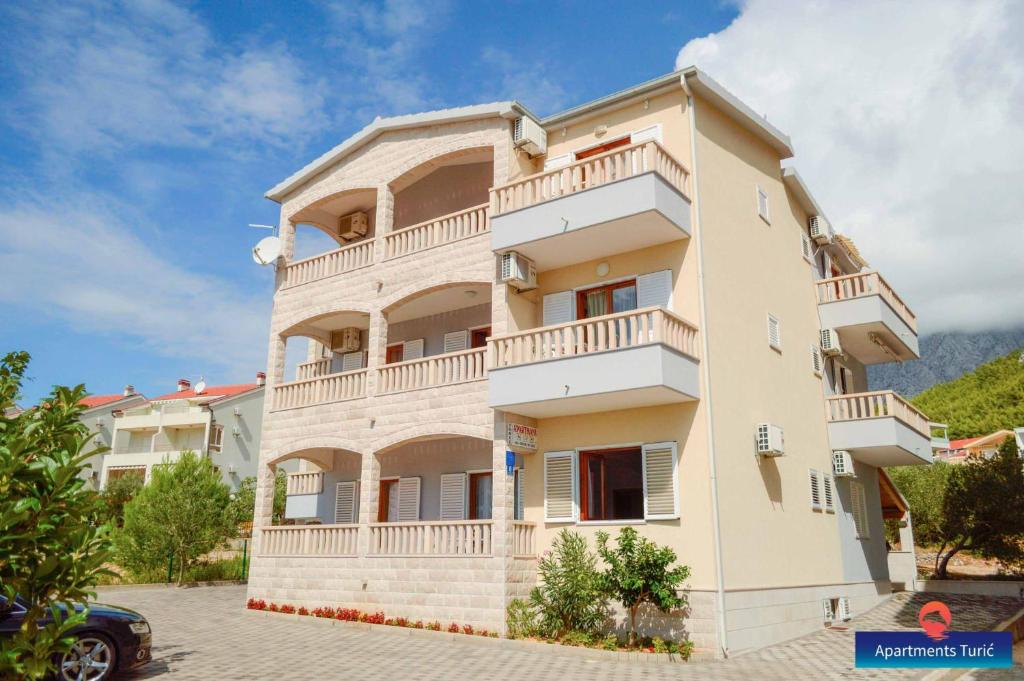 a building with balconies and a car parked in front at Apartments Turić in Promajna