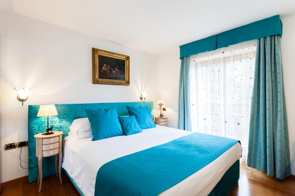 a blue and white bedroom with a bed and a window at Hotel Vienna in San Martino di Castrozza