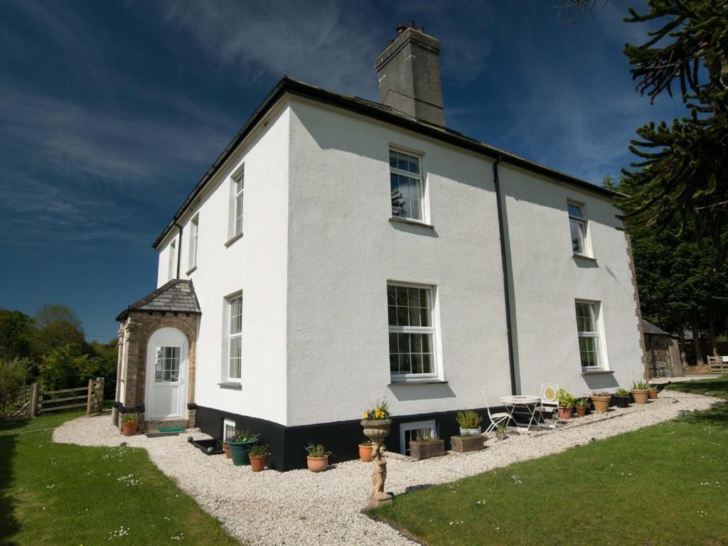 uma casa branca com uma mesa e cadeiras em frente em Poole Farm em Launceston