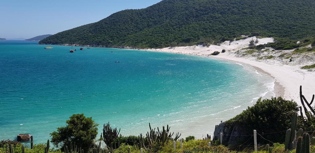 a beach with a white sand and blue water at Apartamento Jamesson Cabo Frio in Cabo Frio