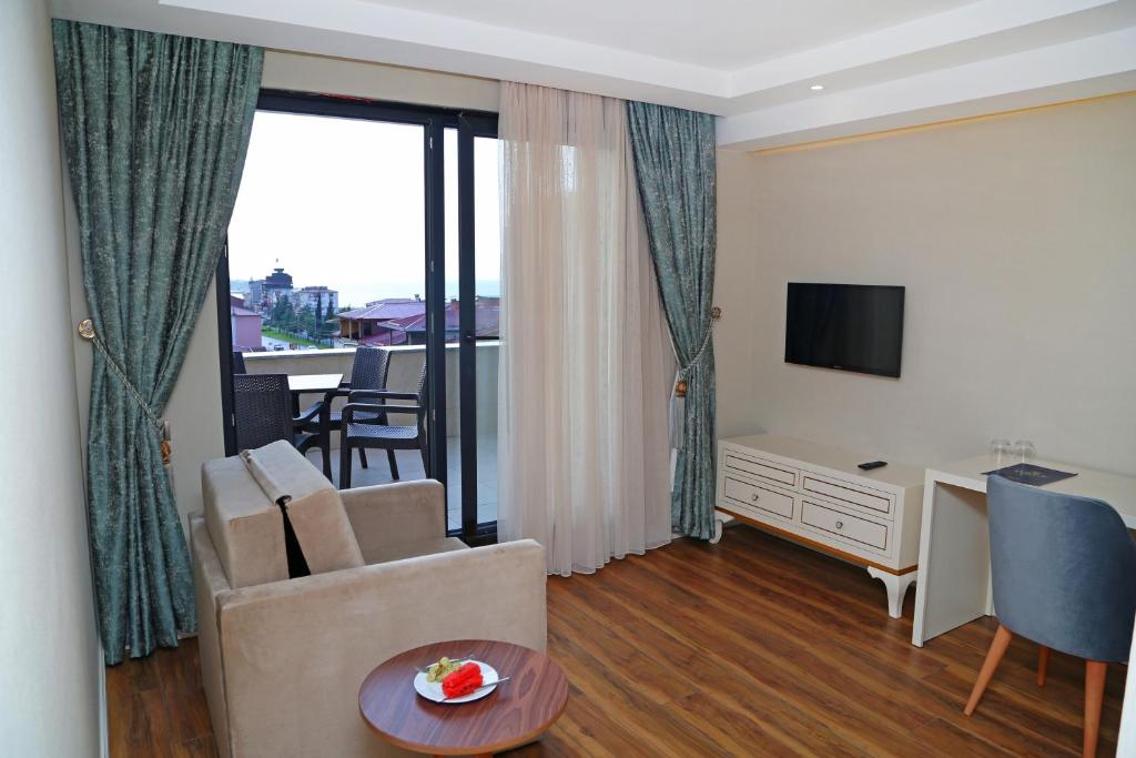 a living room with a couch and a desk and a television at Kubaliç Hotel&SPA in Ordu