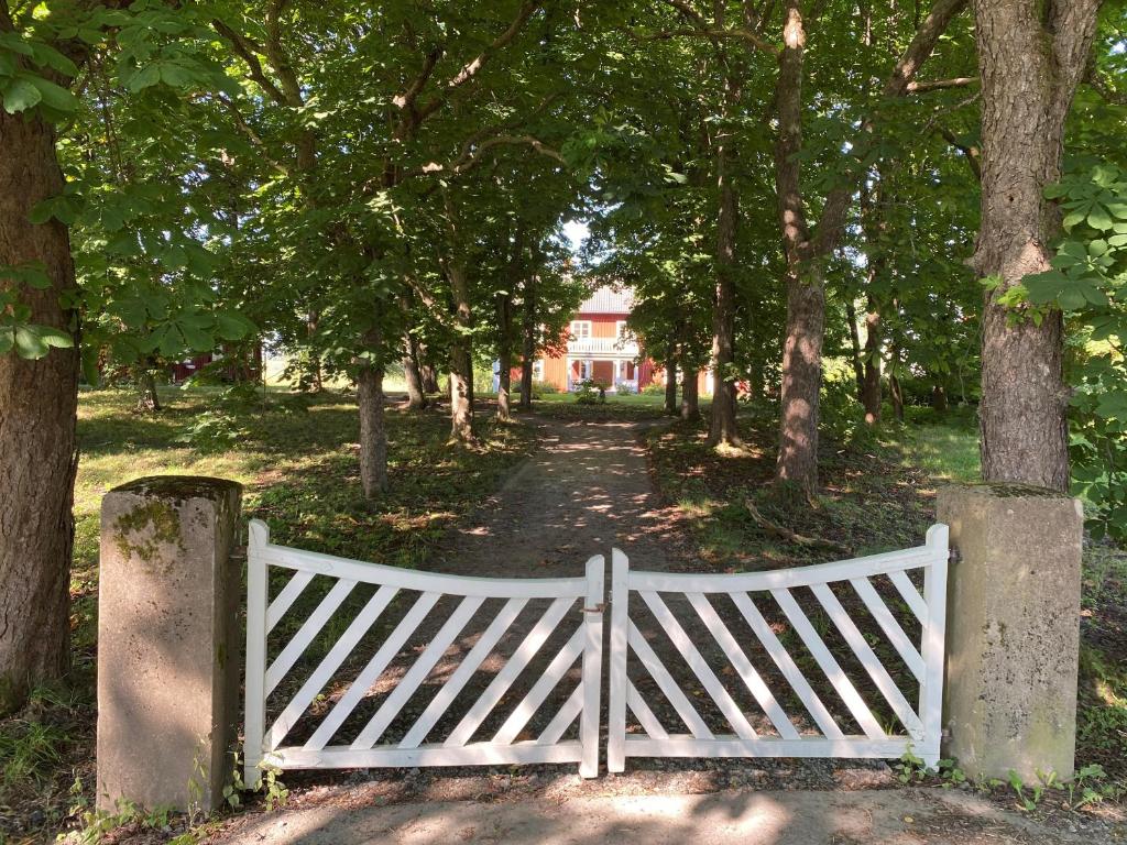 a white gate in the middle of a road with trees at Segerstadsby Gårdshotell AB in Vålberg