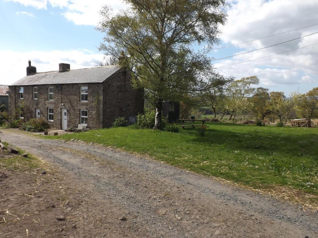 eine unbefestigte Straße vor einem Steinhaus in der Unterkunft Hillis Close Farm Cottage in Haltwhistle
