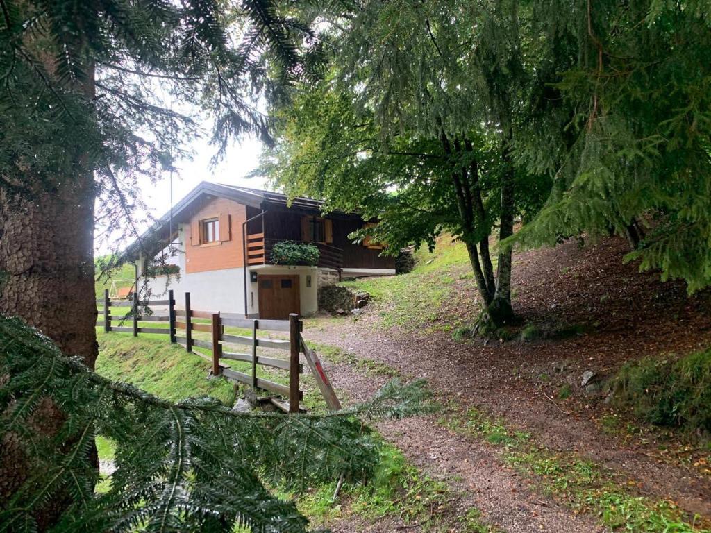 eine Hütte im Wald mit einem Zaun und Bäumen in der Unterkunft La quiete di Tregiovo - CIPAT 22253-AT-34903 in Revò