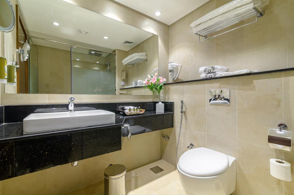 a bathroom with a sink and a toilet and a mirror at Dhafra Beach Hotel in Jebel Dhanna