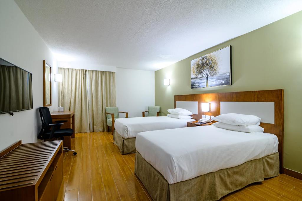 a hotel room with two beds and a desk at Dhafra Beach Hotel in Jebel Dhanna