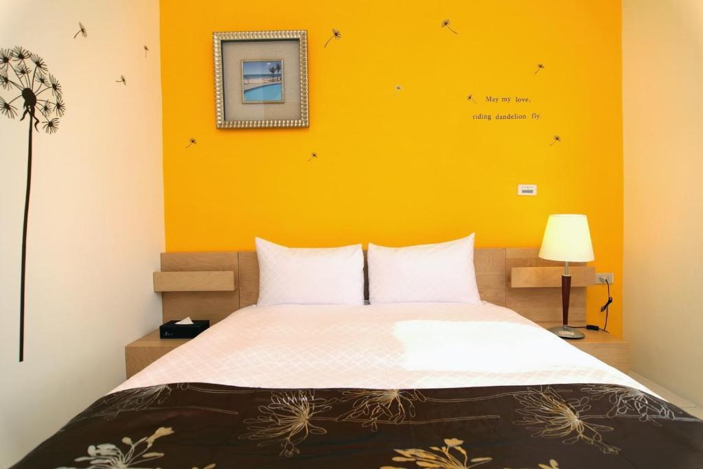 恆春的住宿－Plentiful-Inn Kenting，一间卧室设有一张黄色墙壁的大床