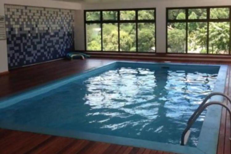 una gran piscina en una habitación con ventanas en Apartamento charmoso com piscina en Gramado