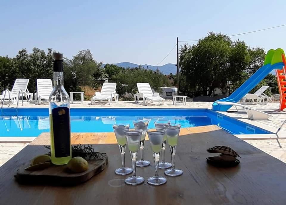 uma garrafa de vinho e copos numa mesa perto de uma piscina em Sreser Domus Nostrae - Peljesac 1 em Sreser
