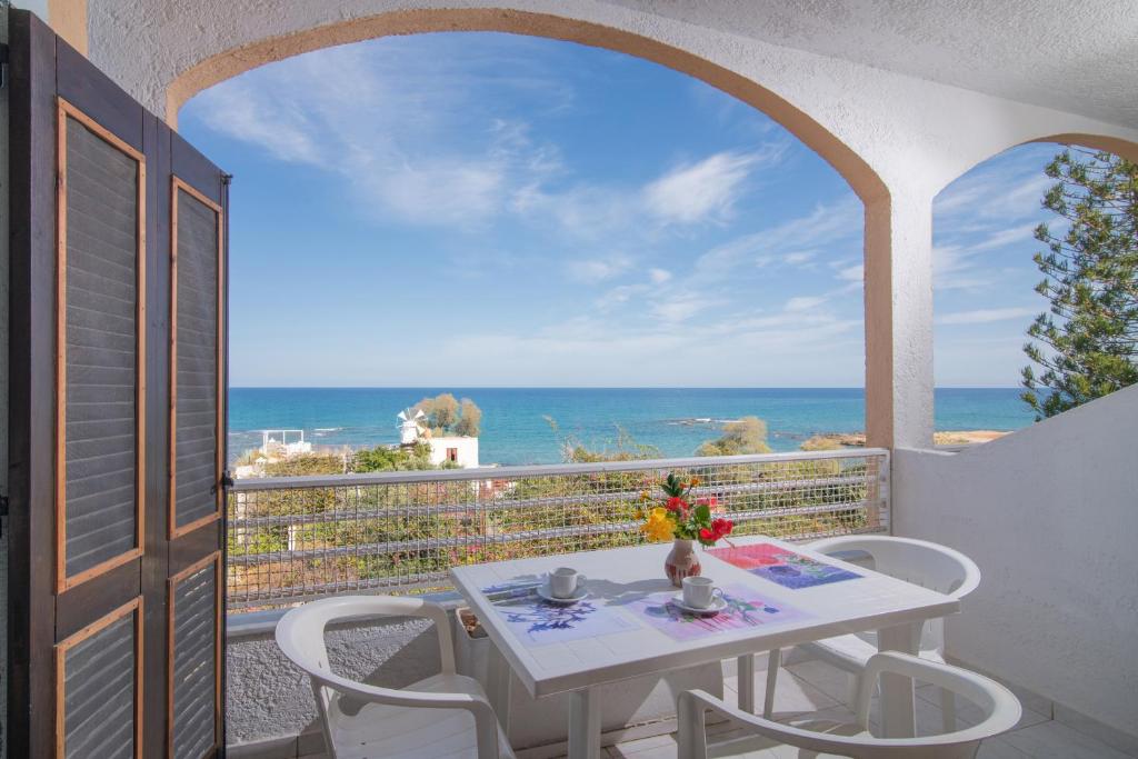 een tafel en stoelen op een balkon met uitzicht op de oceaan bij Iliostasi Beach Apartments in Chersonissos