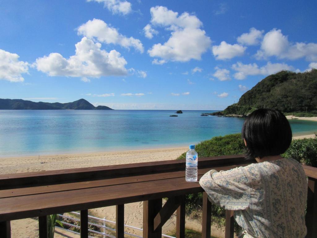 a woman sitting on a fence looking out at the ocean at Amami Lucky House - Vacation STAY 07619v in Amami