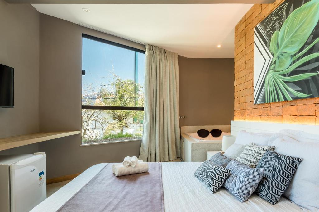 a bedroom with a large window and a bed with pillows at Bravo Pousada Design in Cabo Frio