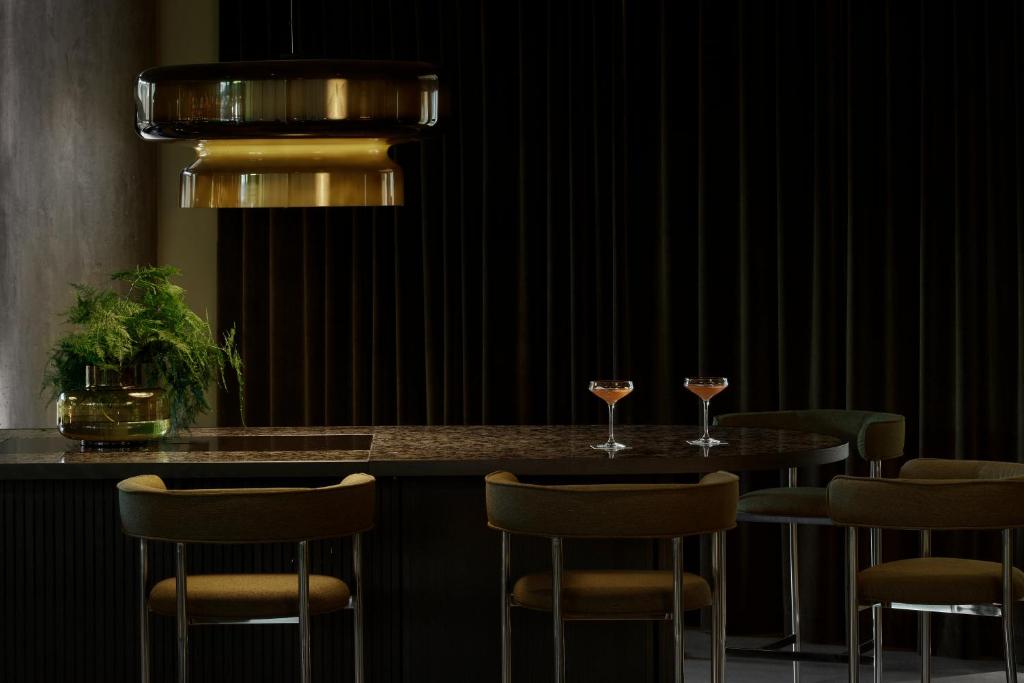 a bar with four chairs and two glasses of wine at VALO Hotel & Work Helsinki in Helsinki