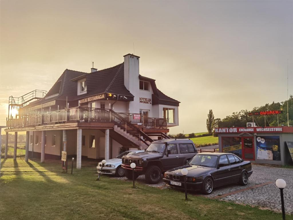 una casa con dos coches estacionados frente a ella en Hotelik Dworek, en Legnickie Pole
