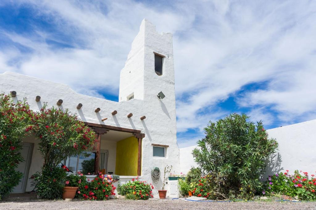 Une église blanche avec des fleurs devant elle dans l'établissement Desert Tracks Rancho, à Las Grutas