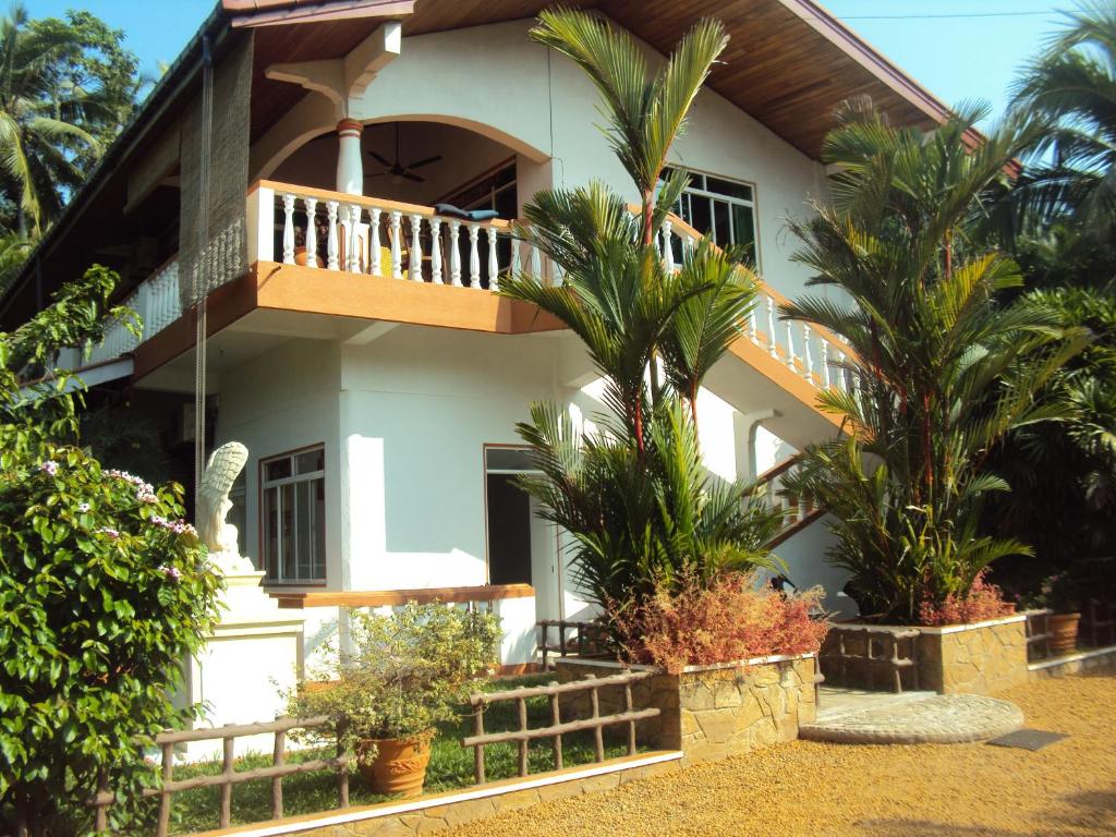 a house with a balcony and some palm trees at Angel Villa in Beruwala