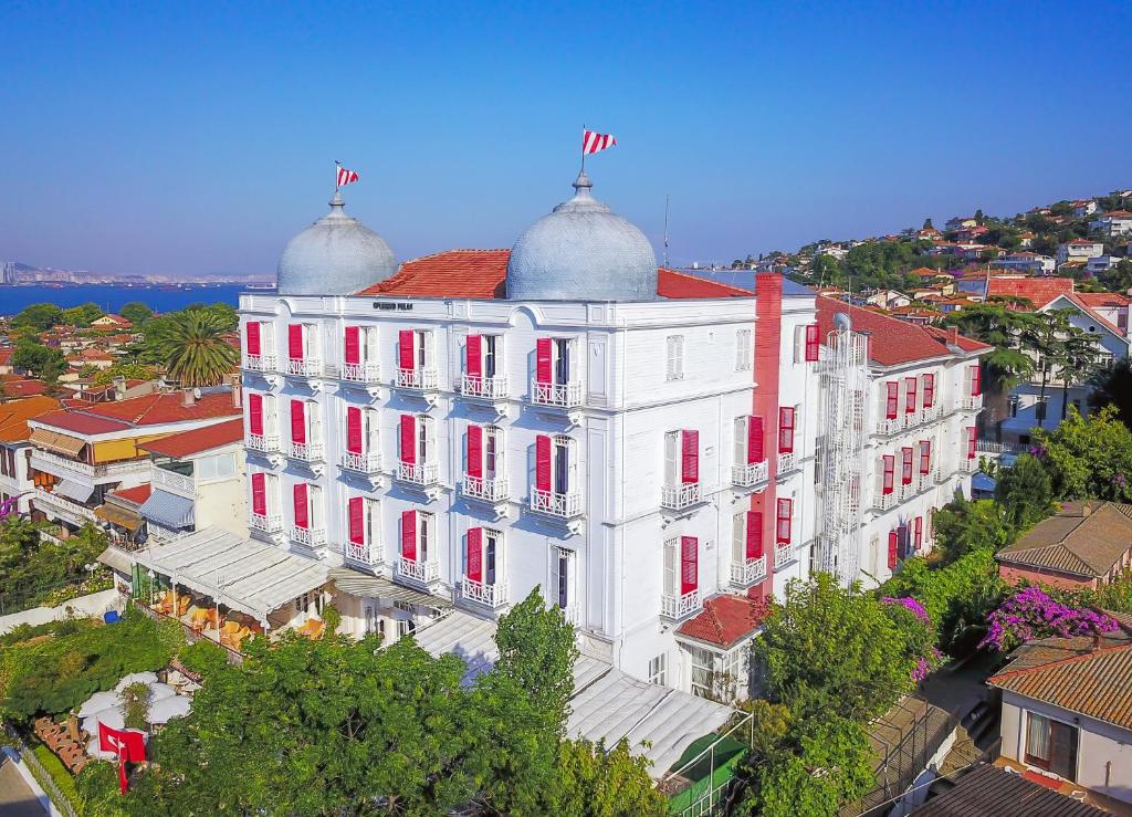 ein großes weißes Gebäude mit roten Fenstern auf einer Stadtstraße in der Unterkunft Splendid Palace in Büyükada