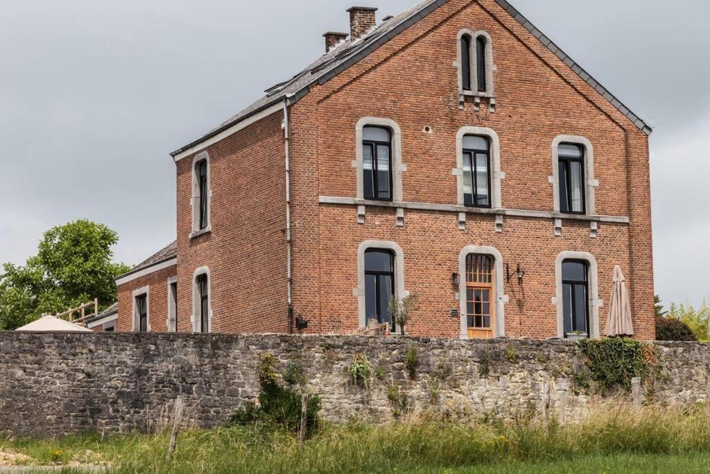 um velho edifício de tijolos atrás de uma parede de tijolos em vakantiewoning maison doute em Durbuy