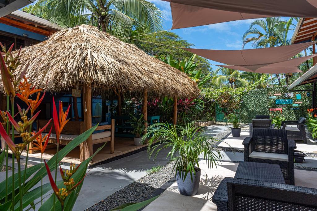 ein Restaurant mit einem Strohschirm, Stühlen und Pflanzen in der Unterkunft Point Break Santa Teresa in Playa Santa Teresa