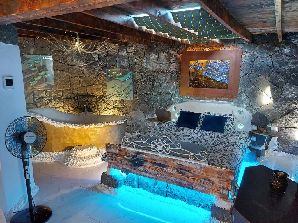 1 dormitorio con cama y pared de piedra en ALOELUXVILLA COM " I " , for couples! Design by the local artist Salvado r, en Conil
