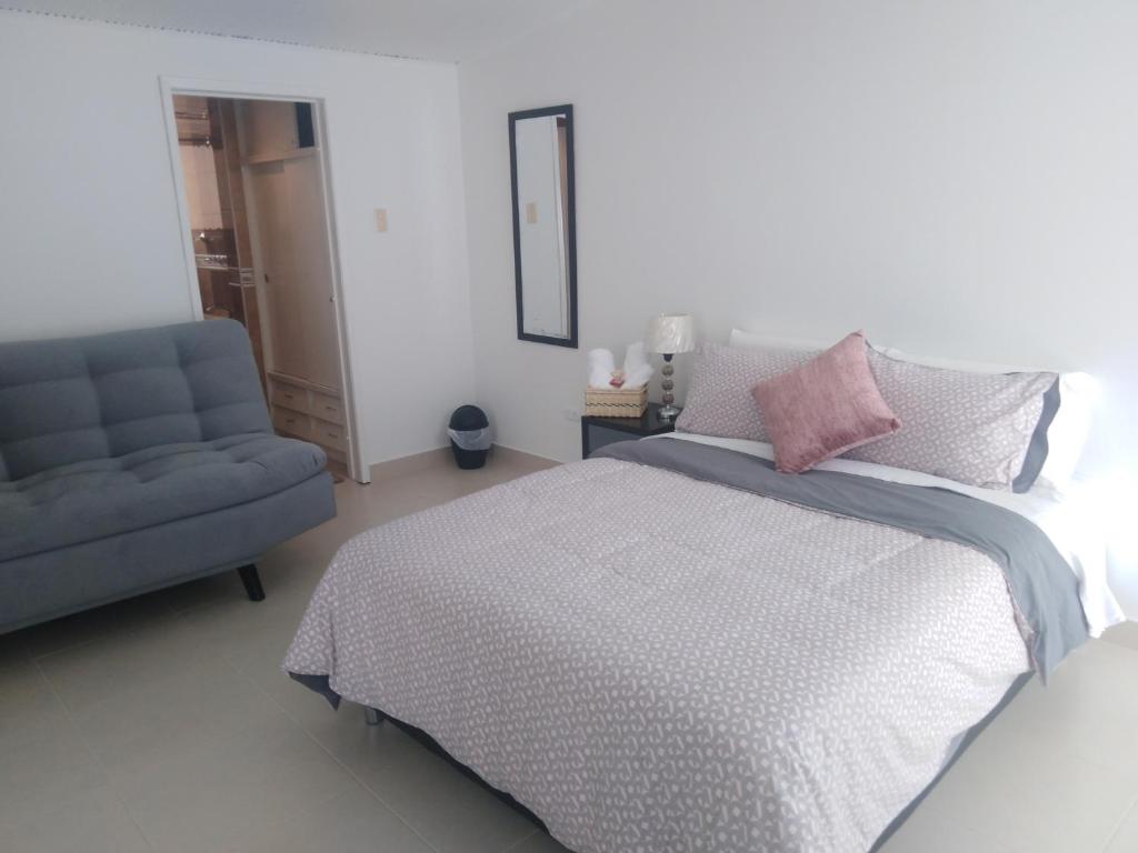 1 dormitorio con 1 cama y 1 silla azul en Casa Coffice, en Bogotá