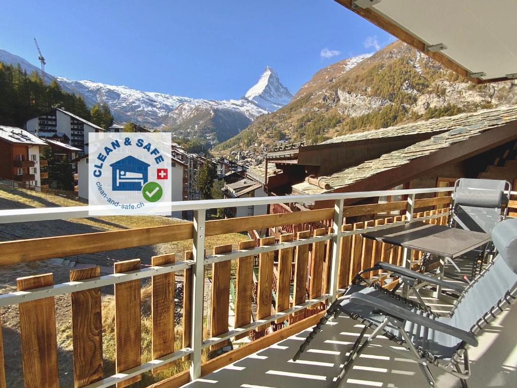 uma varanda com mesa, cadeiras e montanhas em Haus Belmont em Zermatt
